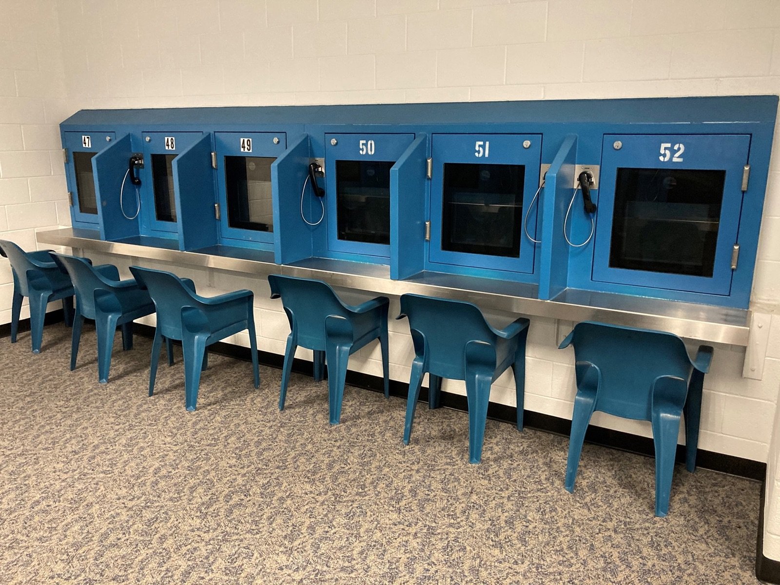 A row of wall-mounted telephone handsets in a bare visiting room at Rappahannock Regional Jail.